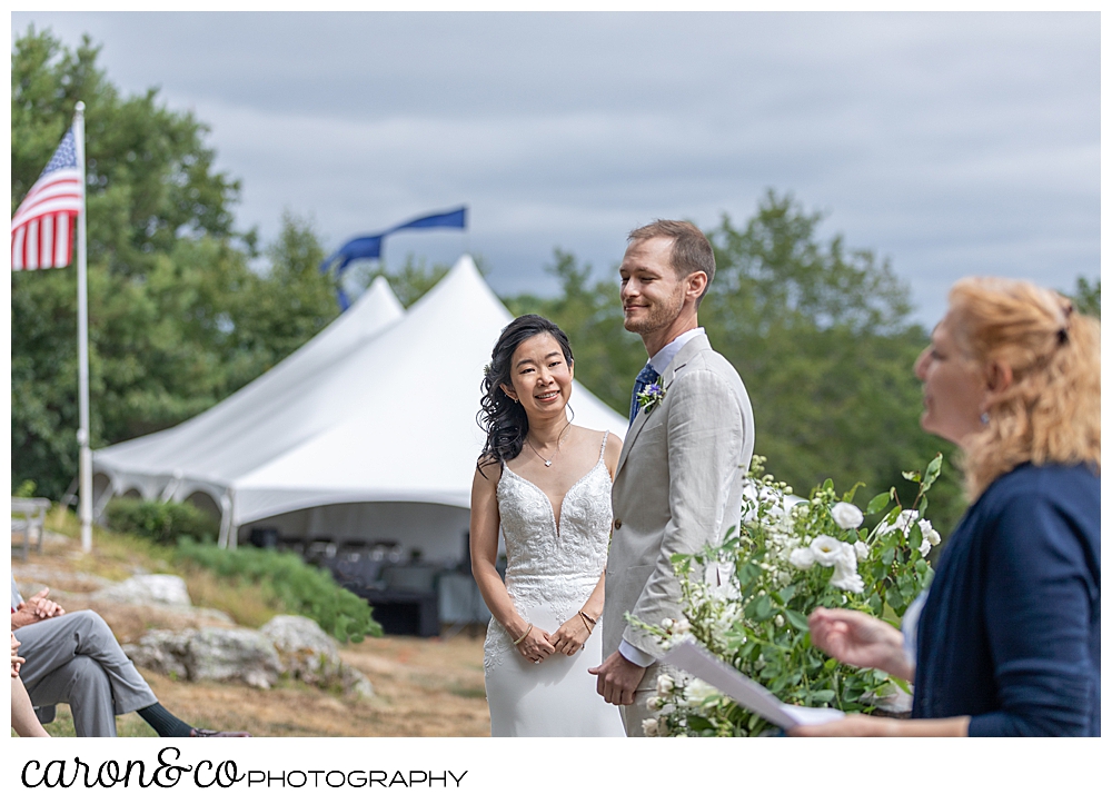 Bride and groom standing together during their Grey Havens Inn wedding ceremony, on the lawn in Georgetown Maine