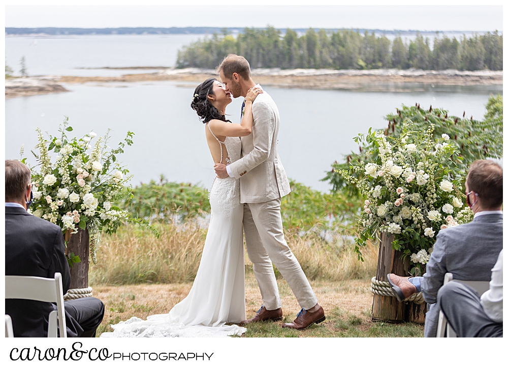 bride and grooms first kiss at their Grey Havens wedding ceremony on the lawn at Georgetown Maine