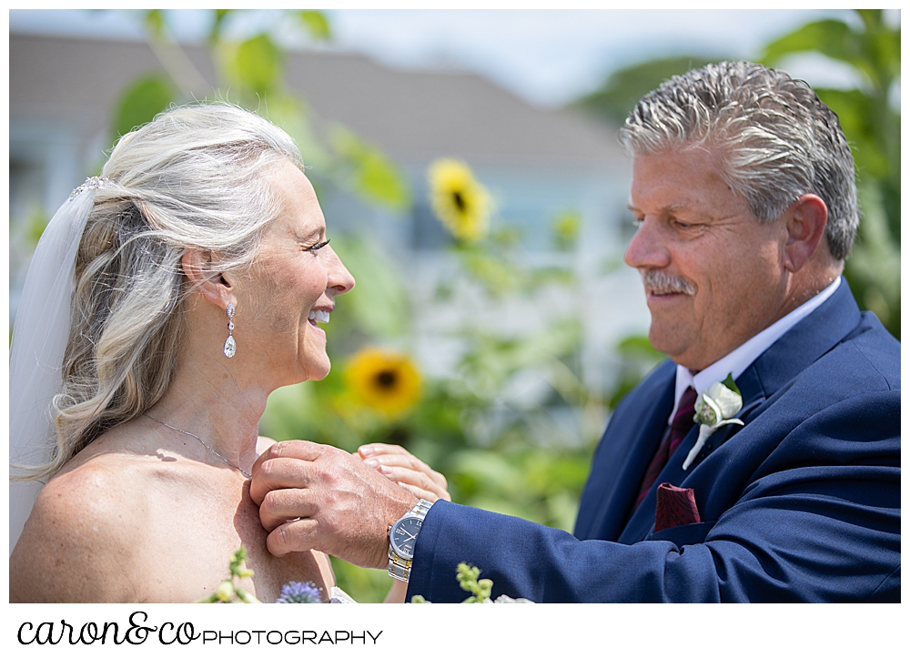 groom puts a necklace around his bride's neck during their wedding day first look