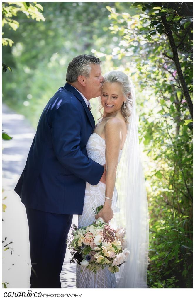 groom kissing his bride on her temple