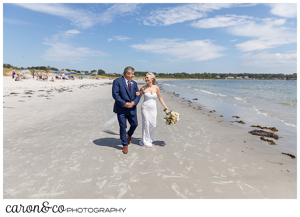 bride and groom walking toward the camera, along the beach 