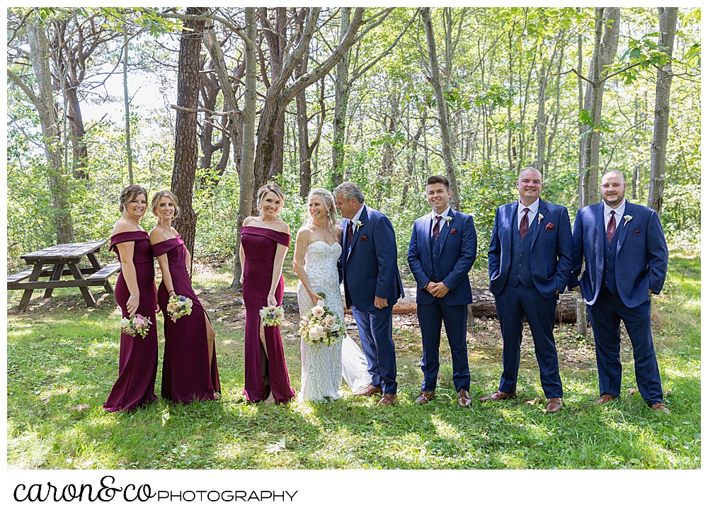 bride and groom pose with their bridal party in the woods