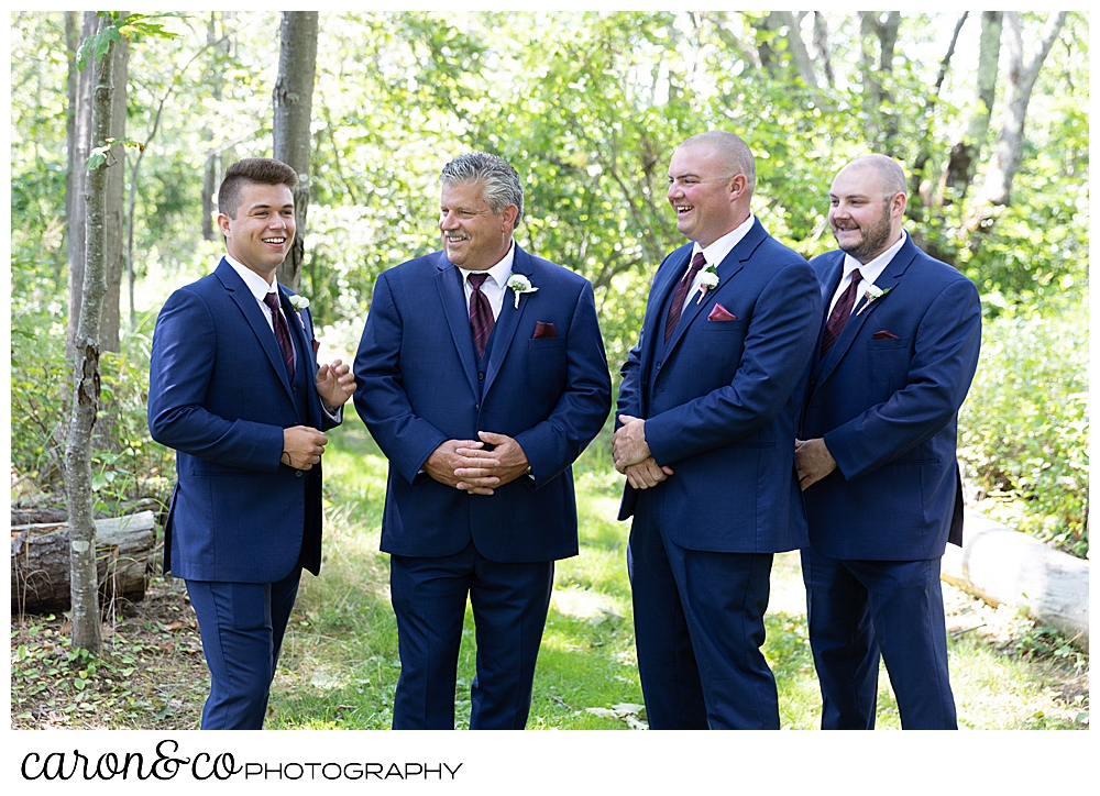 groom, and groomsmen in blue suits, stand together in the woods