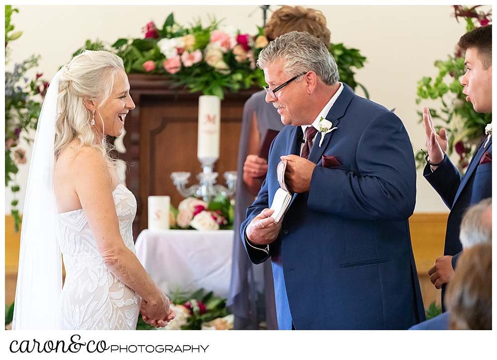 bride smiles at groom, as he takes his vows out during their spurwink church cape elizabeth maine wedding ceremony