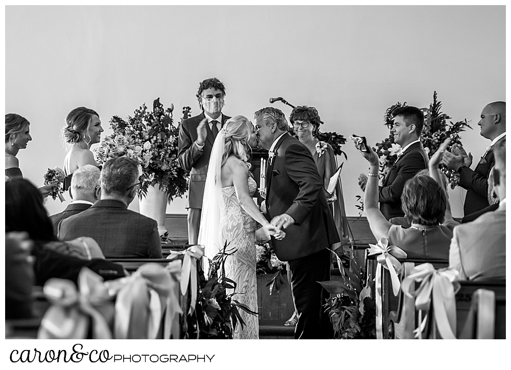 black and white photo of a bride and groom's first kiss at the spurwink church cape elizabeth maine wedding ceremony