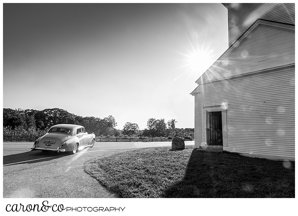 black and white photo of a Maine Limousine Service Bentley driving around the corner of the spurwink church, cape elizabeth, maine