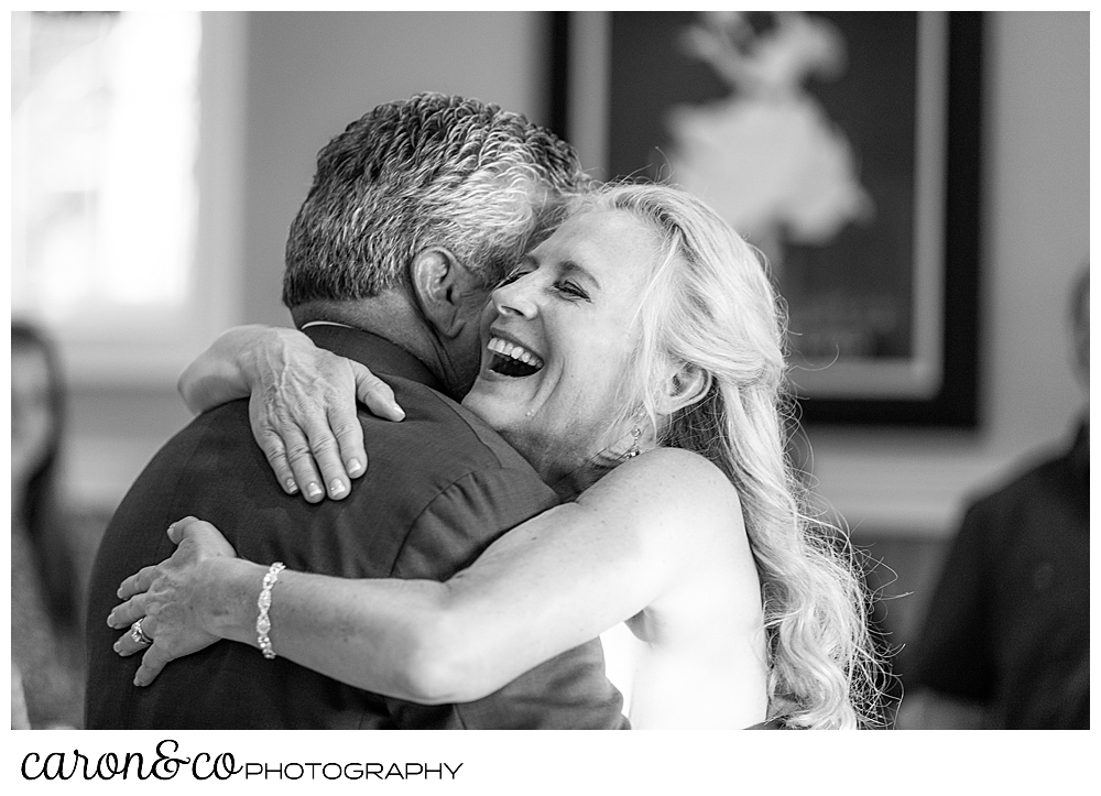 black and white photo of a bride and groom dancing, the bride is laughing