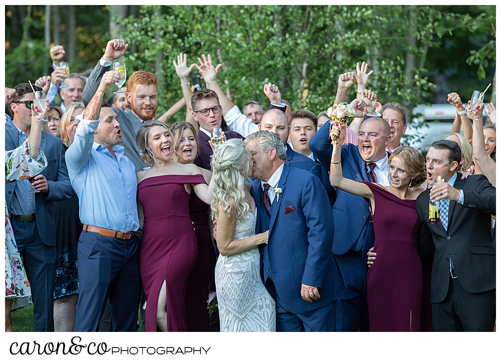 bride and groom kissing while surrounded by their guests