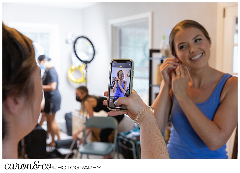 sweet summertime wedding bridesmaid taking photo of bride getting ready 