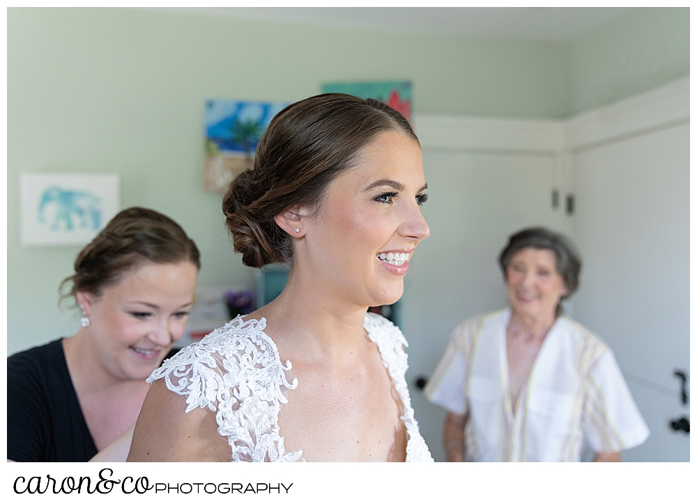 sweet summertime wedding bride getting dressed with her mother and matron of honor