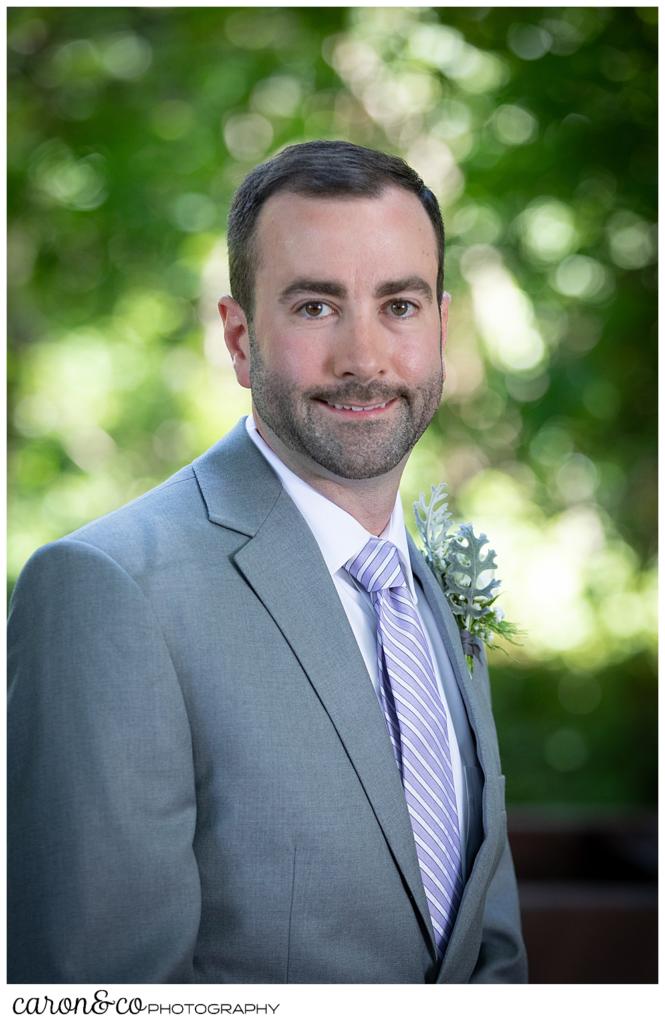 portrait of a groom wearing a gray suit, white shirt, and purple tie