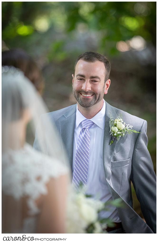 sweet summertime wedding day first look, smiling groom walks toward the bride