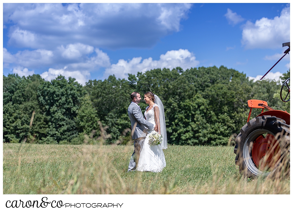 sweet summertime wedding bride and groom kissing in a field near an orange tractor