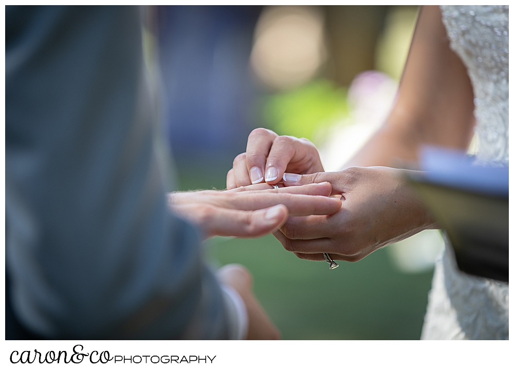 sweet summertime wedding ceremony photo of the bride putting the wedding band on the grooms finger