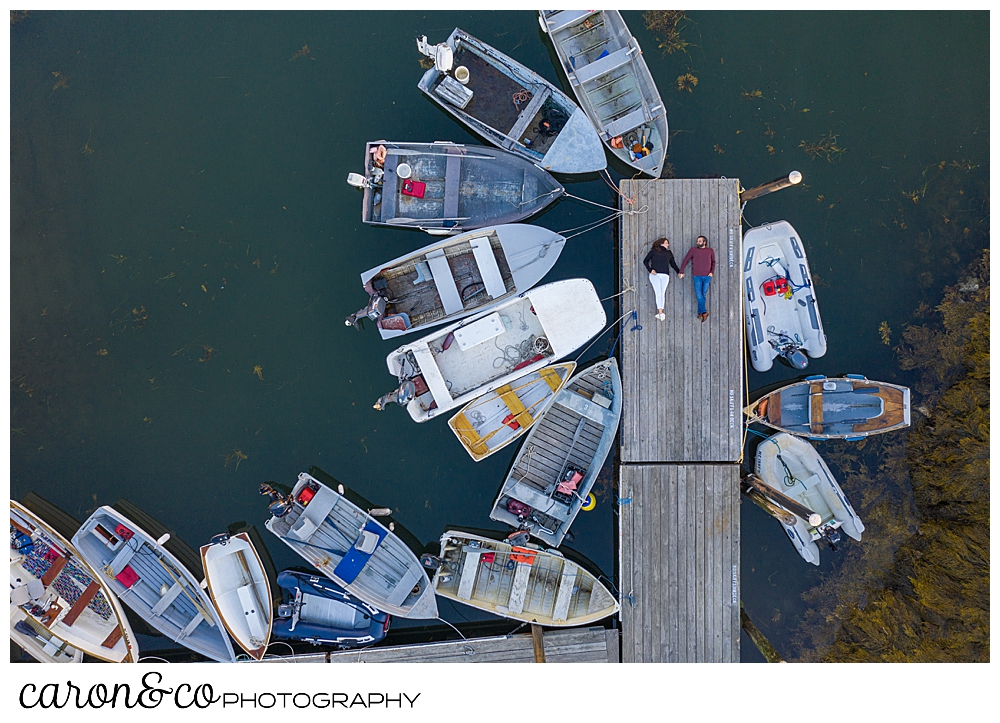 a man and woman are lying on a dock in a Maine drone engagement photo, during their Port Clyde Maine engagement 