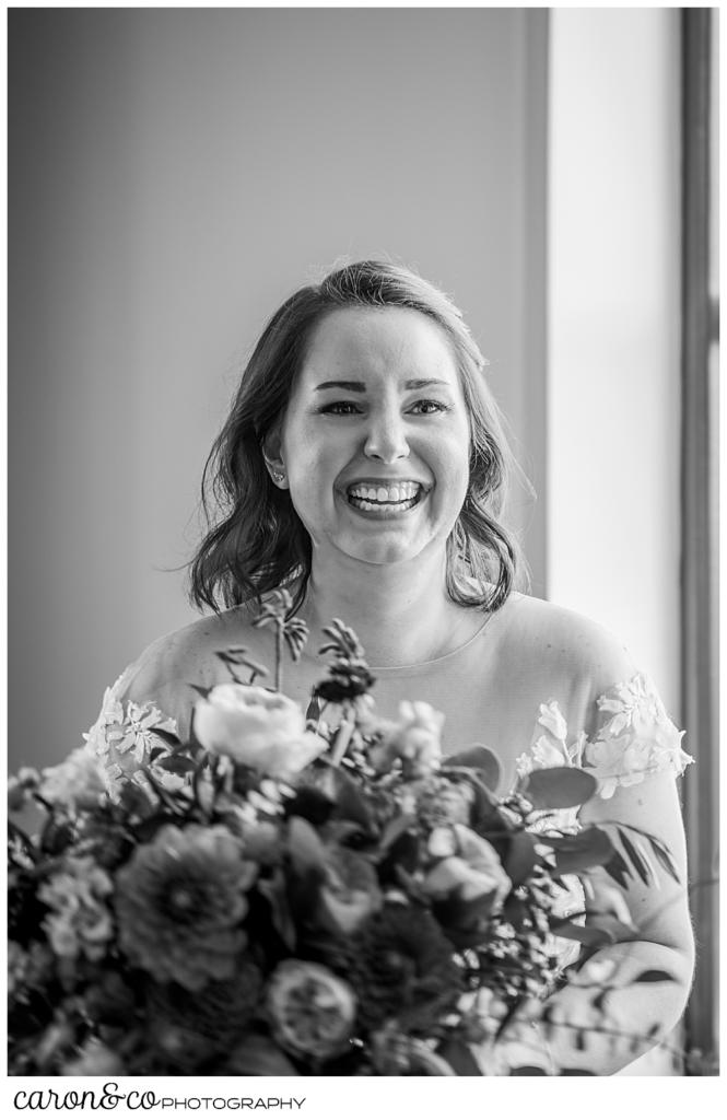 black and white photo of a bride laughing as she holds her bouquet