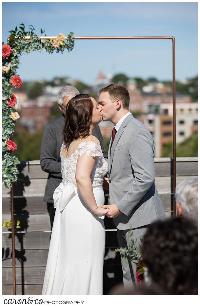 bride and groom's first kiss on the rooftop of their Portland Press Hotel wedding ceremony