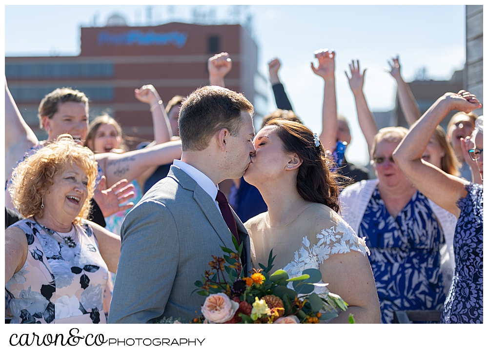 a bride and groom kiss while their guests cheer at a Portland Press Hotel wedding