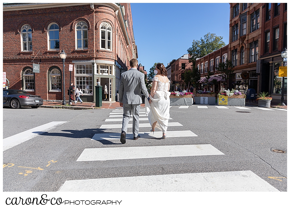 a bride and groom walk across a street in Portland Maine