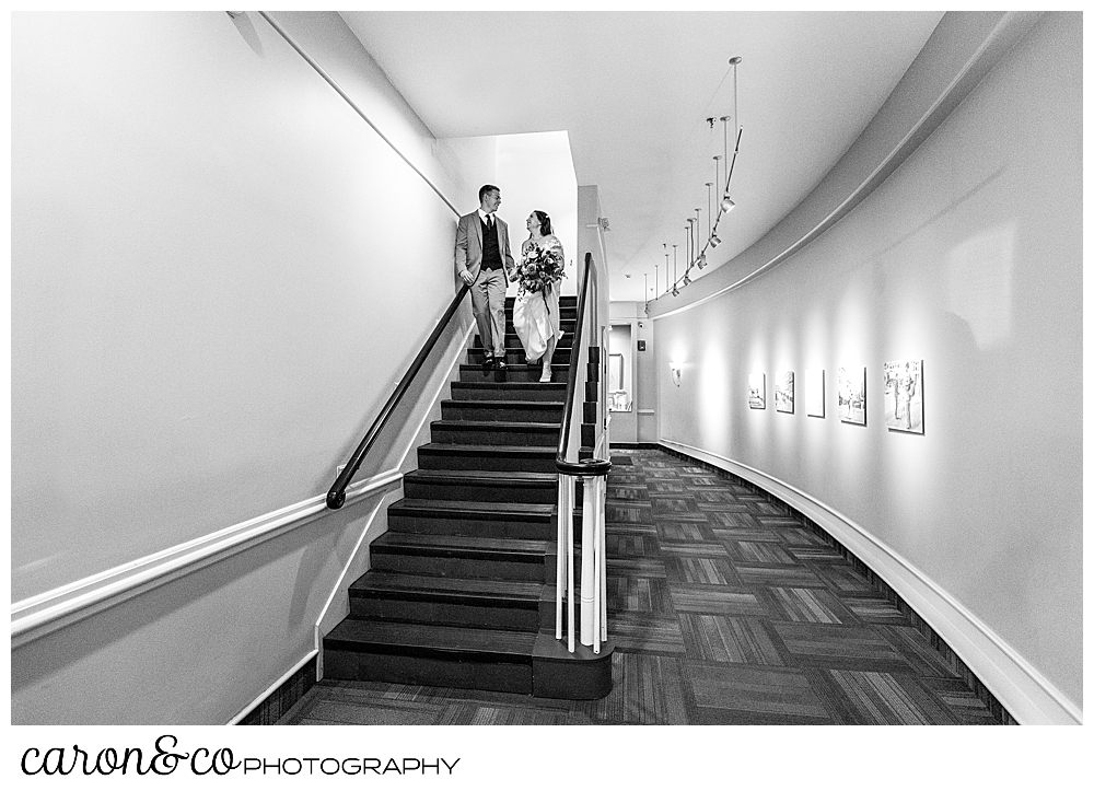 black and white photo of a bride and groom walking down the stairs in an apartment building