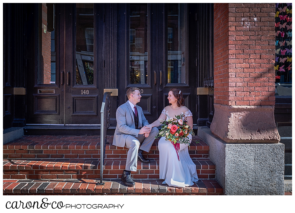 bride and groom sitting on the front steps of an apartment building