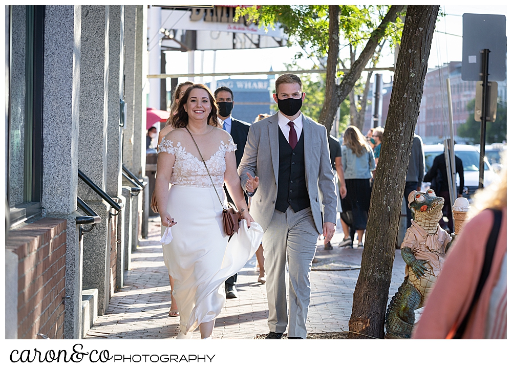 a bride and groom walk down the sidewalk in Portland Maine