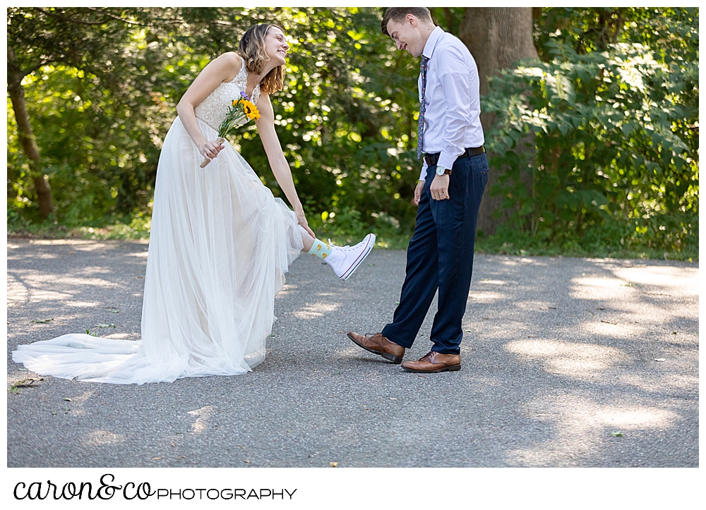 bride living up her foot to show her groom her socks and Converse sneakers