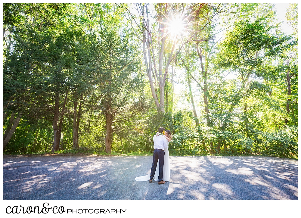 Bride and groom kissing on a road lined with trees