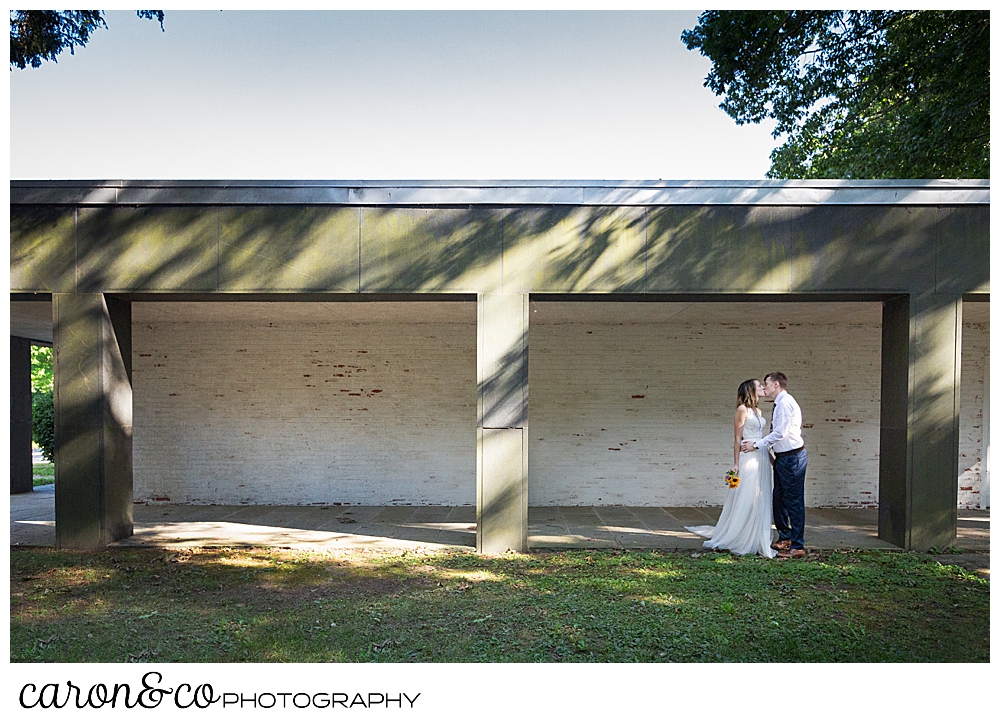 bride and groom kissing each other in front of a building in the woods