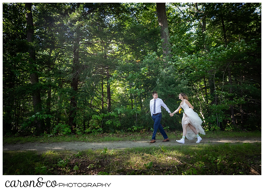 bride and groom walking hand in hand in the woods