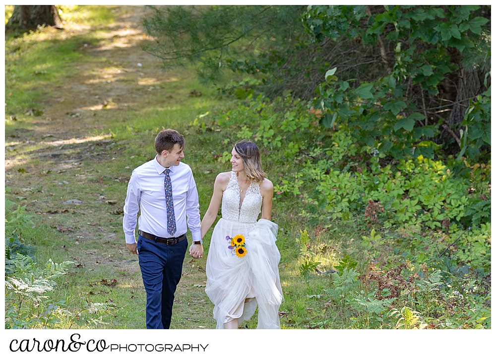 bride and groom walking in the woods, hand in hand