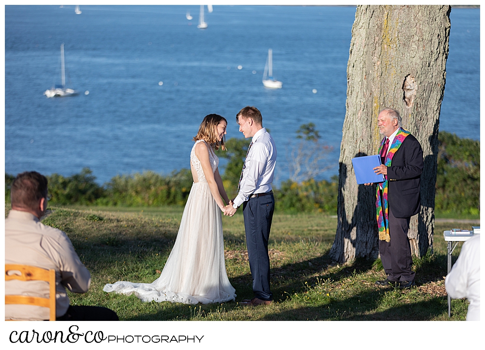 Bride and groom standing together, holding hands, during their sweet Portland Maine elopement ceremony