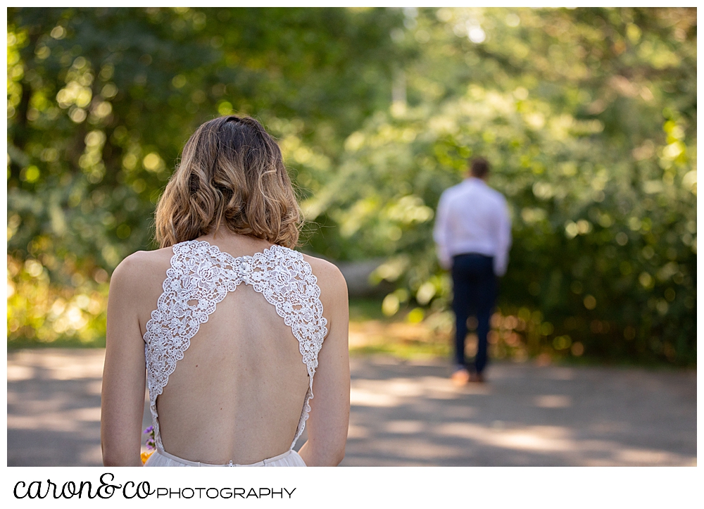 a groom has his back to his bride to be, the bride's back is to the camera as they have a wedding day first look