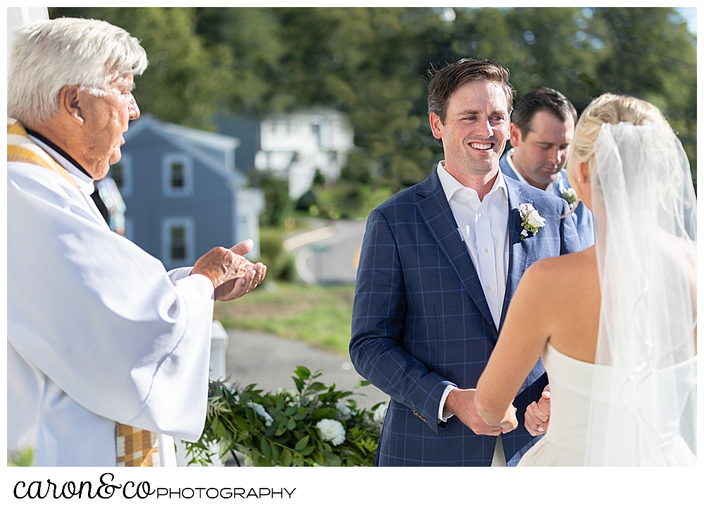 A groom smiles at his bride during their Our Lady Queen of Peace Catholic Church, Boothbay Harbor, Maine