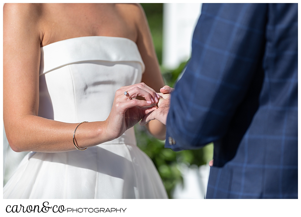 A bride puts a wedding band on her groom's finger during an Our Lady Queen of Peace Catholic Church, Boothbay Harbor, Maine wedding