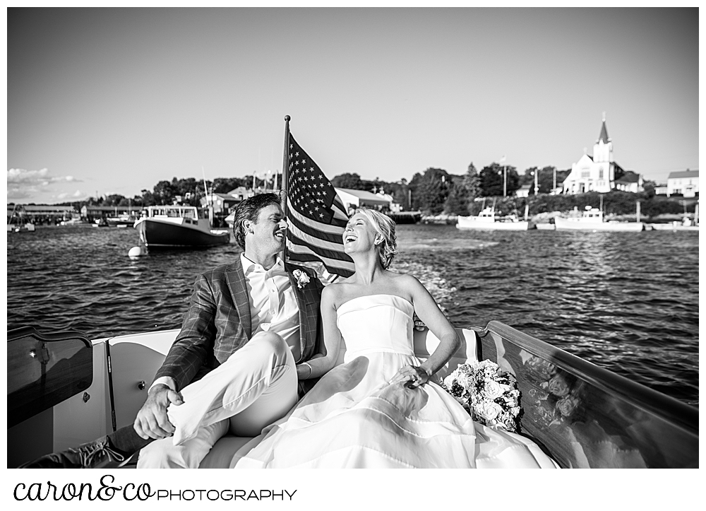 Black and White phot of a bride and groom laughing together as they ride on a Hinckley Yachts Picnic Boat, during their timeless Boothbay harbor wedding, Boothbay Harbor, Maine