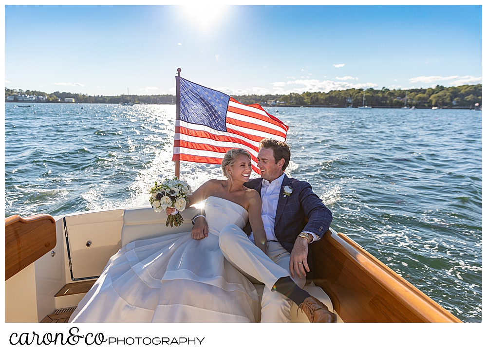 A bride and groom sit on a settee on the back of a Hinckley Yachts Picnic boat at their timeless Boothbay Harbor wedding, Boothbay Harbor, Maine