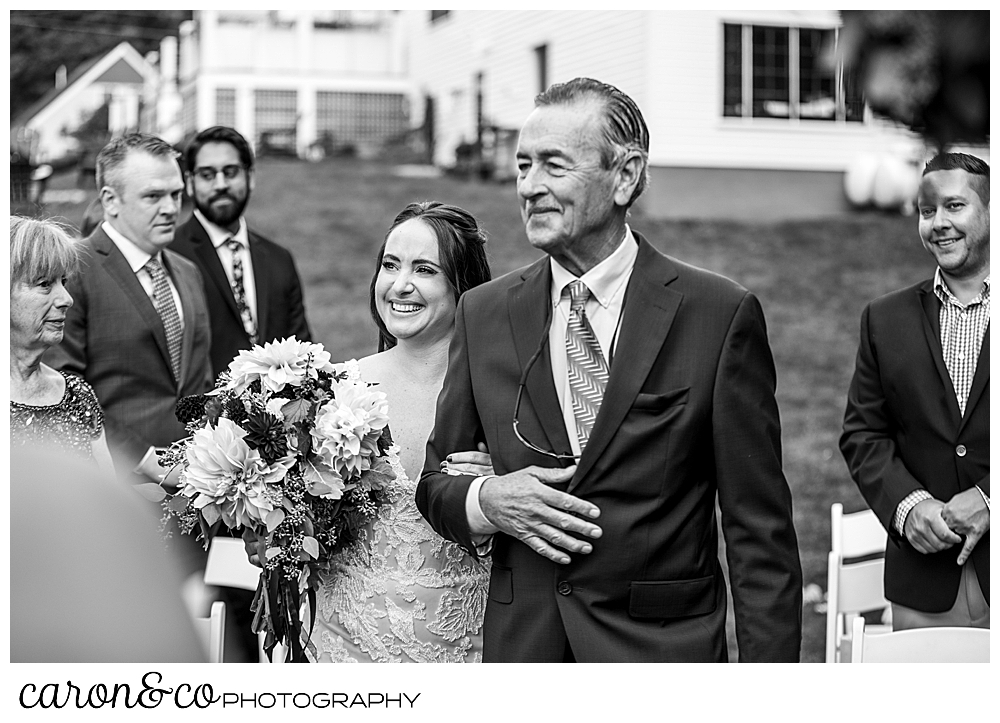 black and white photo of a bride and her father walking down the aisle during a charming Kennebunkport Maine wedding ceremony