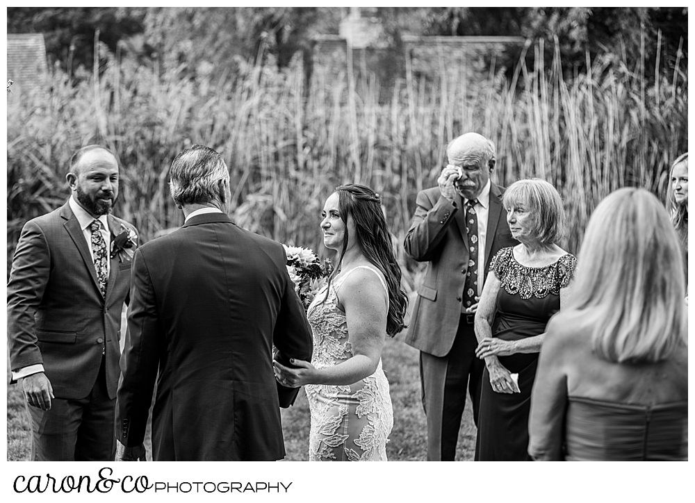 black and white photo of the father of the bride handing the bride off to the groom, at a charming Kennebunkport Maine wedding ceremony