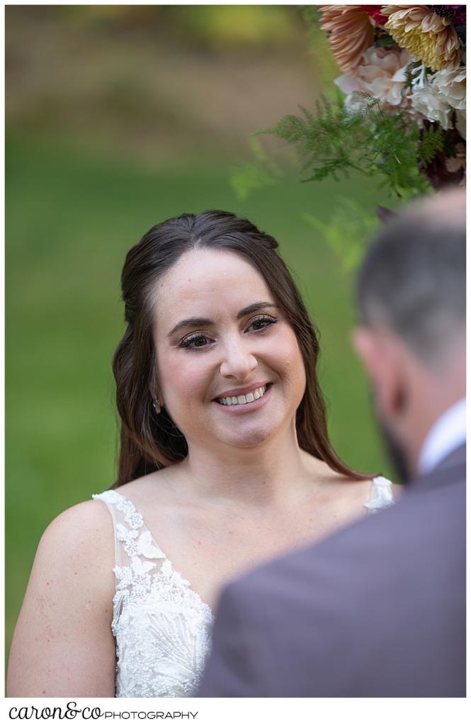 a bride smiles at her groom during their wedding ceremony