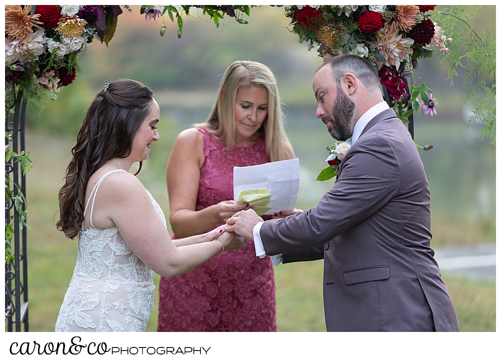 a groom puts the wedding band on the bride's finger during their Kennebunkport Maine wedding ceremony