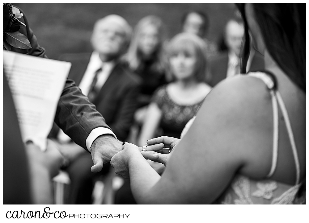 black and white photo of a bride putting the wedding band on the groom's finger