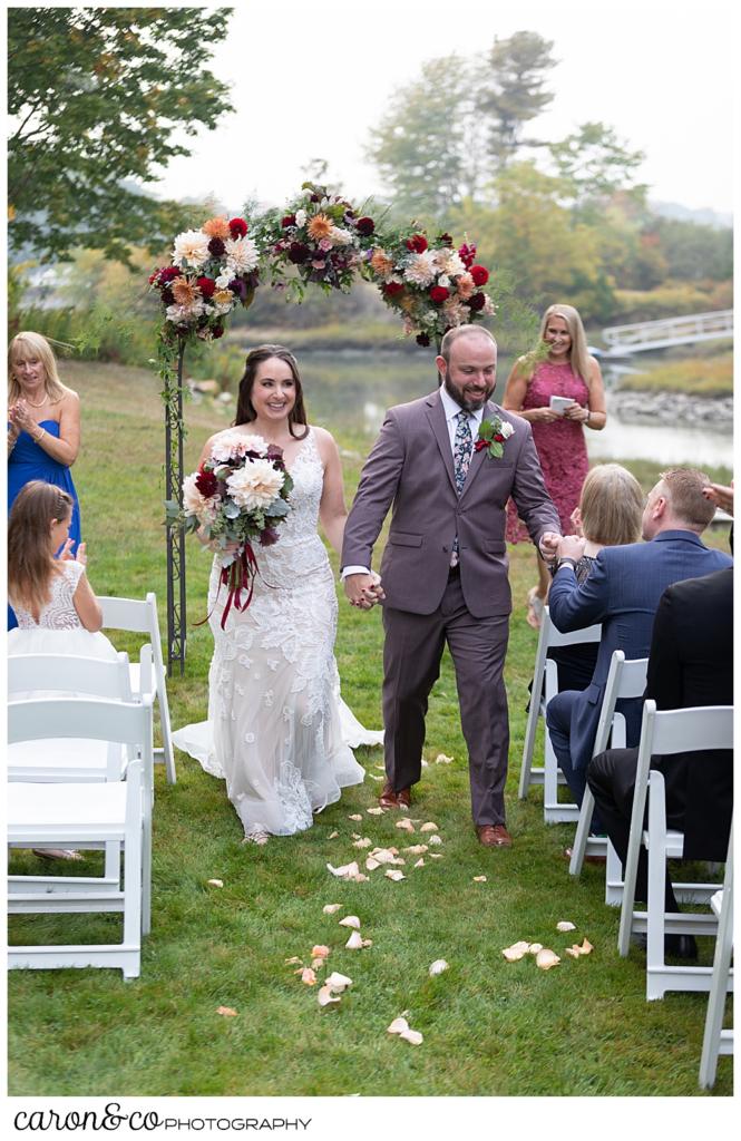 bride and groom during the recessional, the groom reaches out to fist bump a friend sitting in the aisle