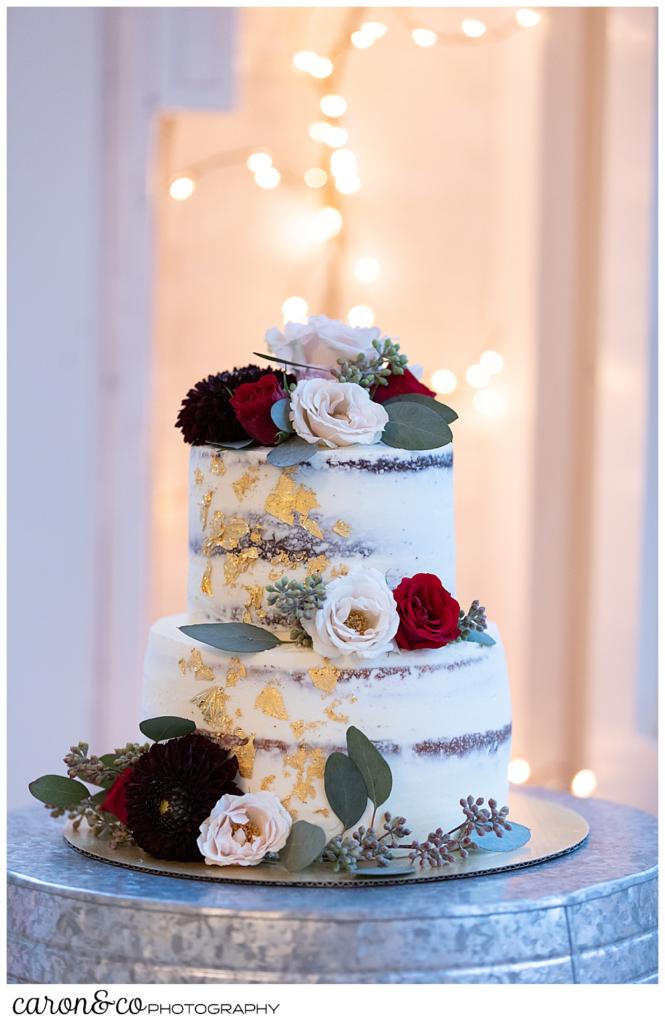 a beautiful wedding cake, with pink and dark red flowers