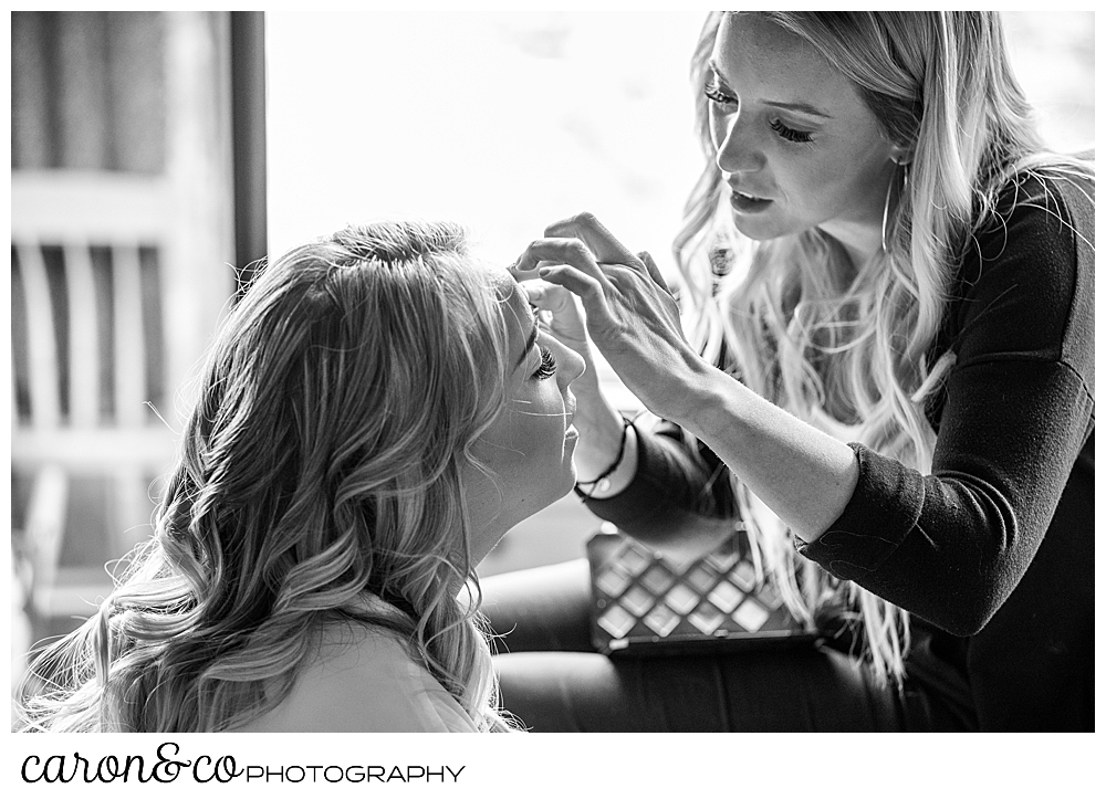 black and white photo of a makeup artist applying eye makeup on a bride