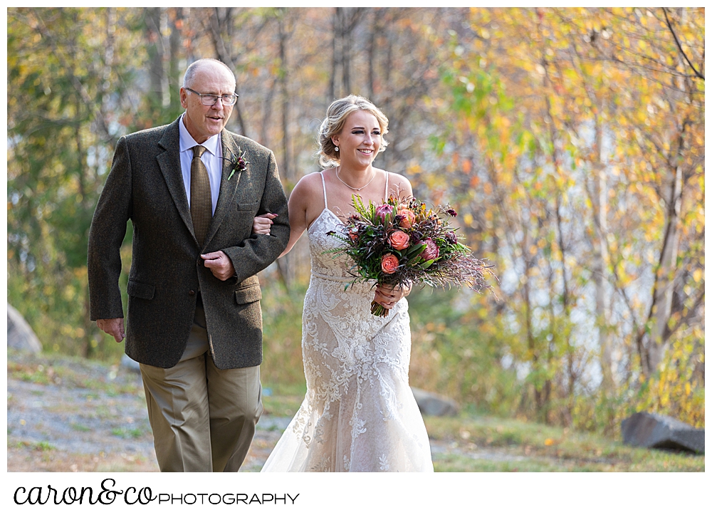 a bride and her father, arm in arm, walk down the aisle at a Rangely Maine wedding