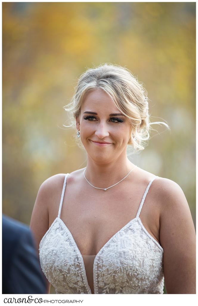 a gorgeous, blonde bride smiles at her groom during their Rangeley Maine wedding ceremony