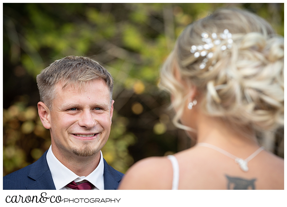 a groom smiles at his bride during their Rangeley Maine outdoor wedding ceremony