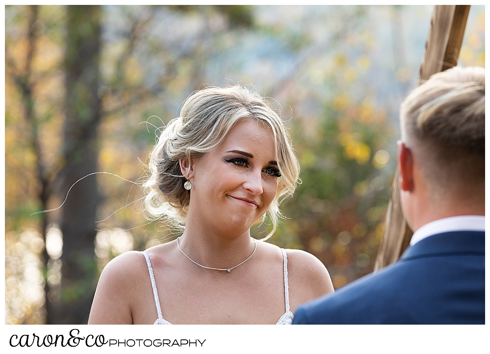 a bride smiles at her groom during their outdoor Rangeley Maine wedding ceremony