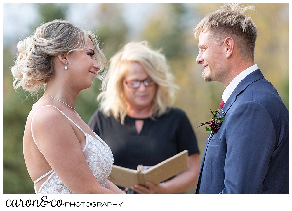 a bride and groom stand together in front of their officiant during their Rangeley Maine wedding ceremony